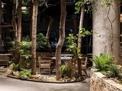 Industrial-style restaurant interior with concrete, wooden tables and chairs, and glass elements.
