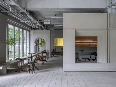 A modern restaurant bar interior with concrete walls and seating areas.