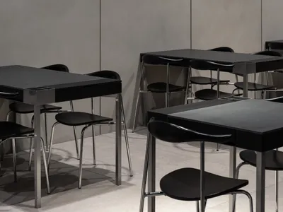 Modern, minimalist industrial restaurant interior with metal tables and chairs.