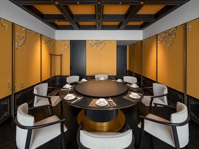 A modern, industrial-themed restaurant interior featuring a metal frame and round dining table surrounded by white upholstere