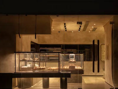 A minimalist restaurant interior featuring glass, concrete, and metal elements.