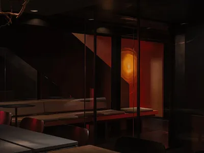 Modern restaurant interior with dark lighting and glass walls, showcasing sophisticated design elements.