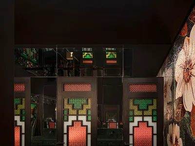 The front entrance of a modern restaurant featuring intricate stained-glass doors with geometric patterns.