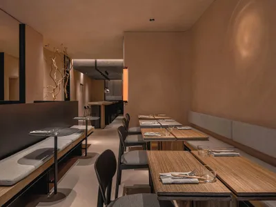 Modern minimalist restaurant interior with wooden benches and fabric seating