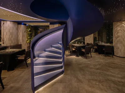 A modern restaurant interior featuring metallic walls and circular designs.