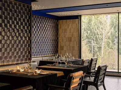 Modern restaurant interior featuring steel tile walls and black leather seating