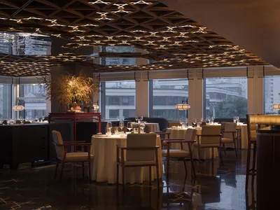 Modern restaurant interior with metal ceiling and round tables.