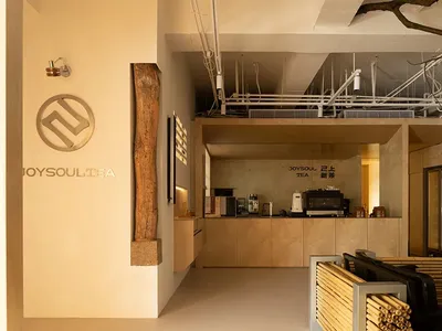 Seating area with industrial-style tables, metal chairs, and exposed wood and concrete surfaces.