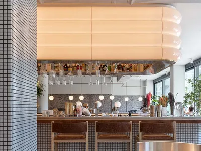A modern restaurant bar counter featuring a tile top and minimalist design.