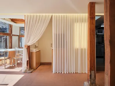 A modern restaurant interior featuring a toilet area with curtain lighting and wooden beams