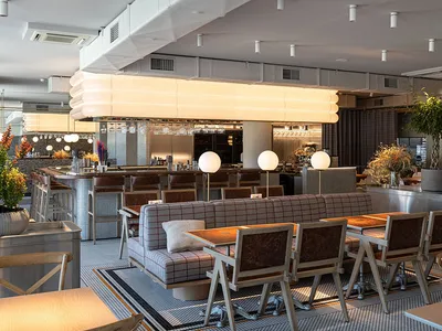 An industrial-style restaurant interior with metallic furniture and a long bar counter.