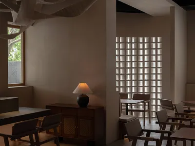 簡約餐廳室內空間，搭配木製餐桌、餐椅與木櫃及燈具，搭配布面覆蓋的橫樑