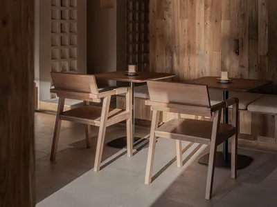 Two wooden chairs and tables in a modern restaurant interior