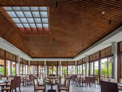 A spacious restaurant interior featuring wooden elements and a glass ceiling.