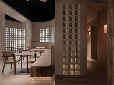 A minimalist restaurant interior featuring wooden tables, chairs, and ceiling beams.