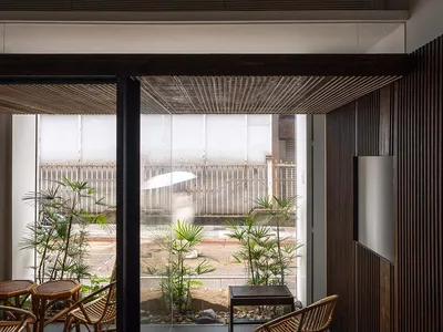 Cafe interior with wooden walls, plants, and rattan furniture.