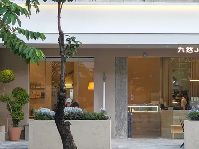 現代咖啡店戶外座位區，採用混凝土與玻璃元素。