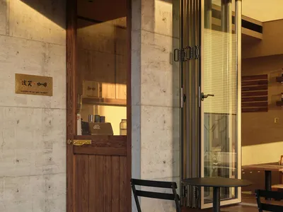 Concrete and wooden entrance to a cafe with seating area