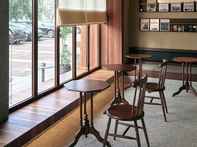 Cafe interior with wooden tables, chairs, and a window with blinds.