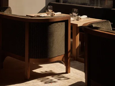 Modern restaurant interior with wooden furniture, tables, chairs, and glasses.
