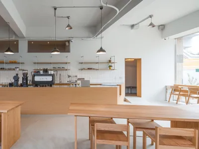 A minimalist restaurant interior featuring wood furniture and shelves.