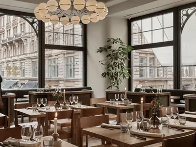 A modern restaurant interior with wooden tables, glass chandeliers, and lit candles.