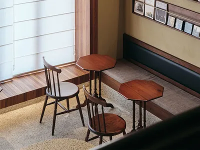 A cozy coffee shop interior with wooden furniture and a seating area by a large window.