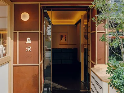 An entrance to a restaurant featuring a metal-clad wooden facade.