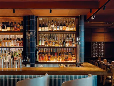 Modern restaurant bar counter featuring blue tiles and a variety of liquor bottles in the background.