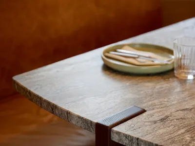 A granite countertop with a wooden support, featuring a plate of cutlery and a glass.