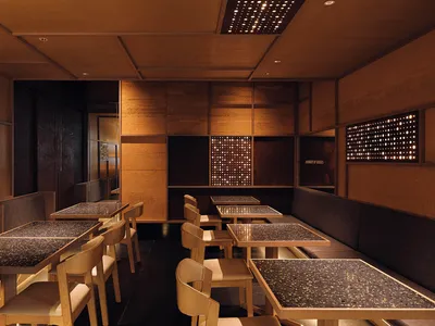 A modern restaurant interior featuring wooden tables and terrazzo flooring.