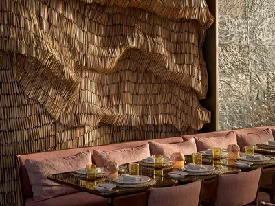 Modern restaurant interior with a textured, wavy wood wall and comfortable seating arrangement.