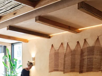 A modern restaurant interior featuring wooden tables, chairs, and decorative wall hangings.