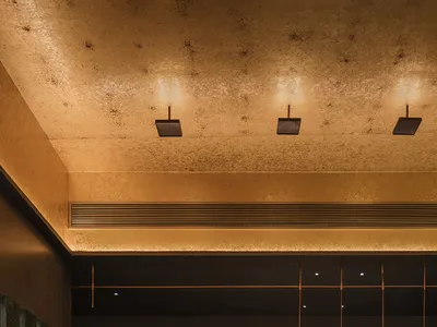 A sleek, modern hotel reception area featuring concrete walls, geometric lighting, and minimalist decor.