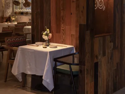 A cozy, industrial-style restaurant interior with wooden walls and a table setup.