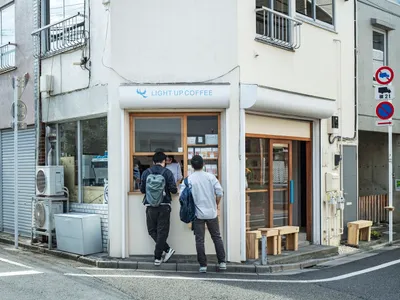 一間現代街角咖啡店，擁有白色牆面與玻璃落地窗。