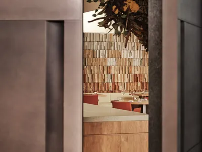 A modern restaurant interior with exposed timber walls and red chairs.
