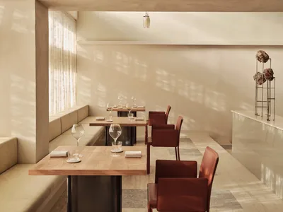 Modern restaurant interior with wooden tables, leather chairs, and concrete flooring and walls