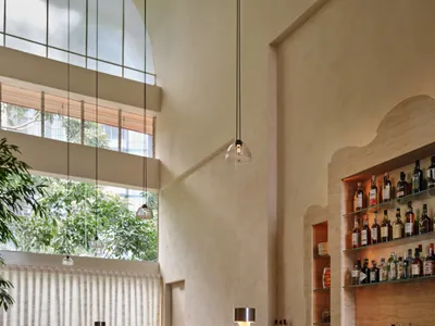 Modern bar with a red marble counter and beige stools.