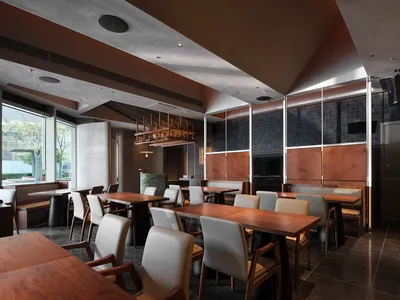 A modern restaurant interior featuring wooden tables and concrete walls.