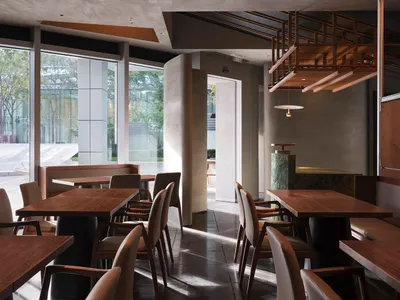 Modern restaurant interior with wooden tables, concrete flooring, and metallic accents.