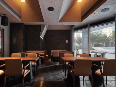 Modern wooden tables and leather chairs in a restaurant dining room.