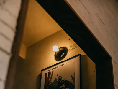 Concrete interior of a coffee shop with framed art depicting a coffee-making scene.