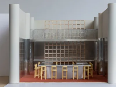 A modern restaurant bar with metal tables and wooden barstools.