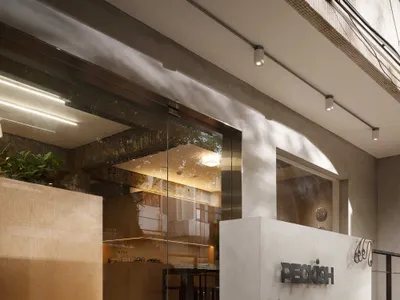 Industrial-style restaurant entrance featuring concrete, glass, and warm lighting.