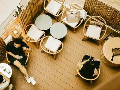 People sitting at bamboo furniture in a cafe with concrete flooring