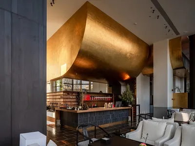 Industrial-themed restaurant bar interior with metallic wall and seating area.