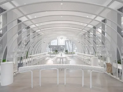 簡約風格的餐廳，擁有白色拱門、金屬餐桌與玻璃牆面。