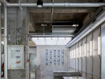 Industrial-style restaurant kitchen with concrete walls, metal countertops, and stainless steel equipment.