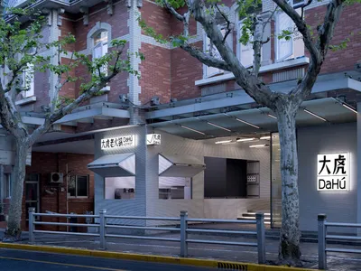 A modern restaurant exterior with a concrete facade, glass windows, and metal railings.